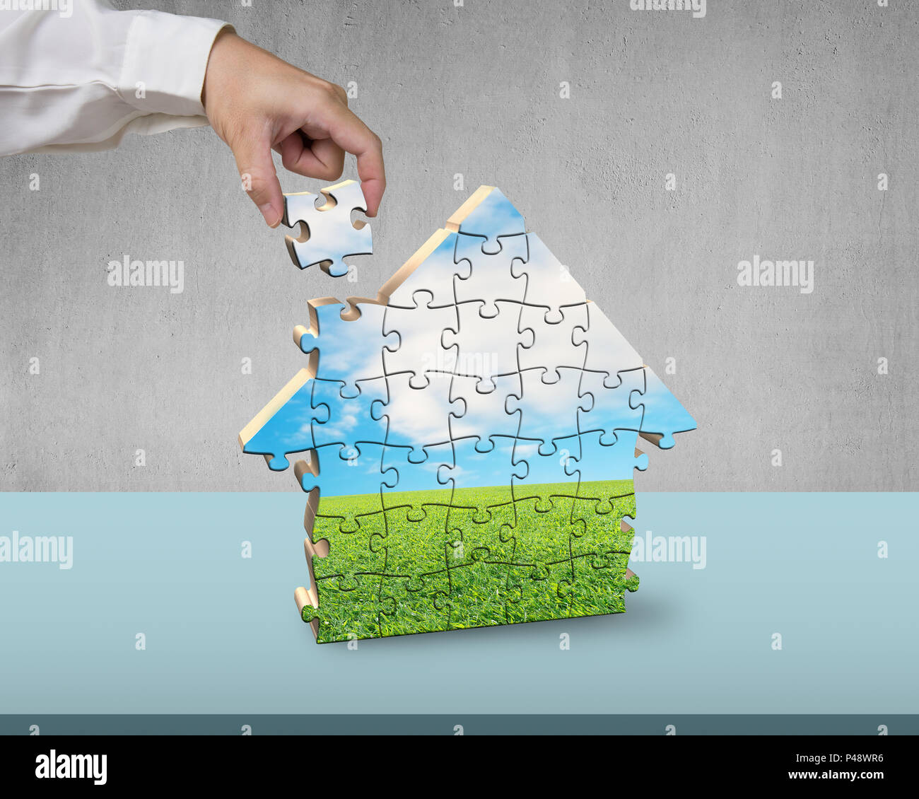 Assembling house shape puzzles on desk Stock Photo