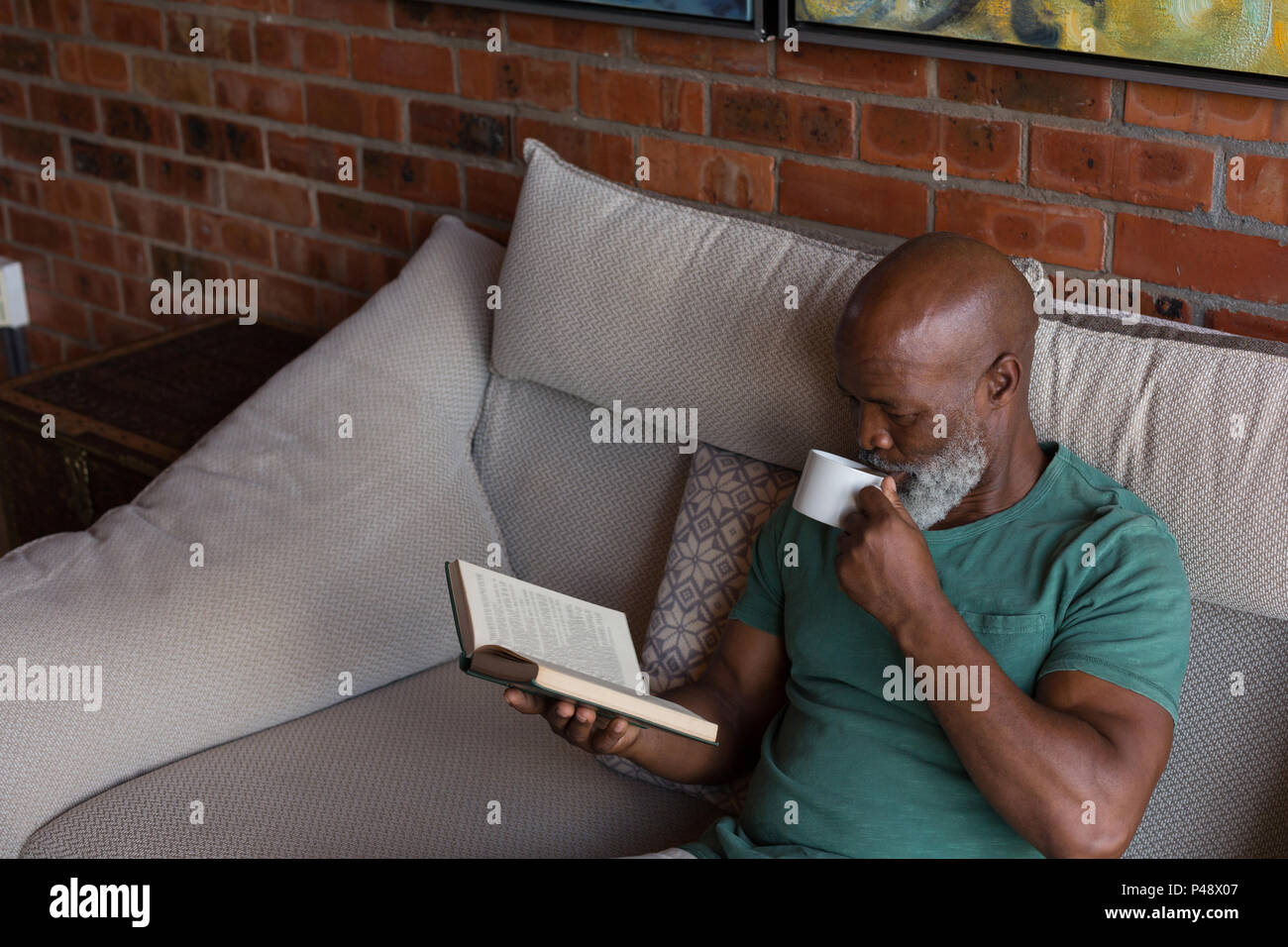 Senior man having coffee while reading a book Stock Photo