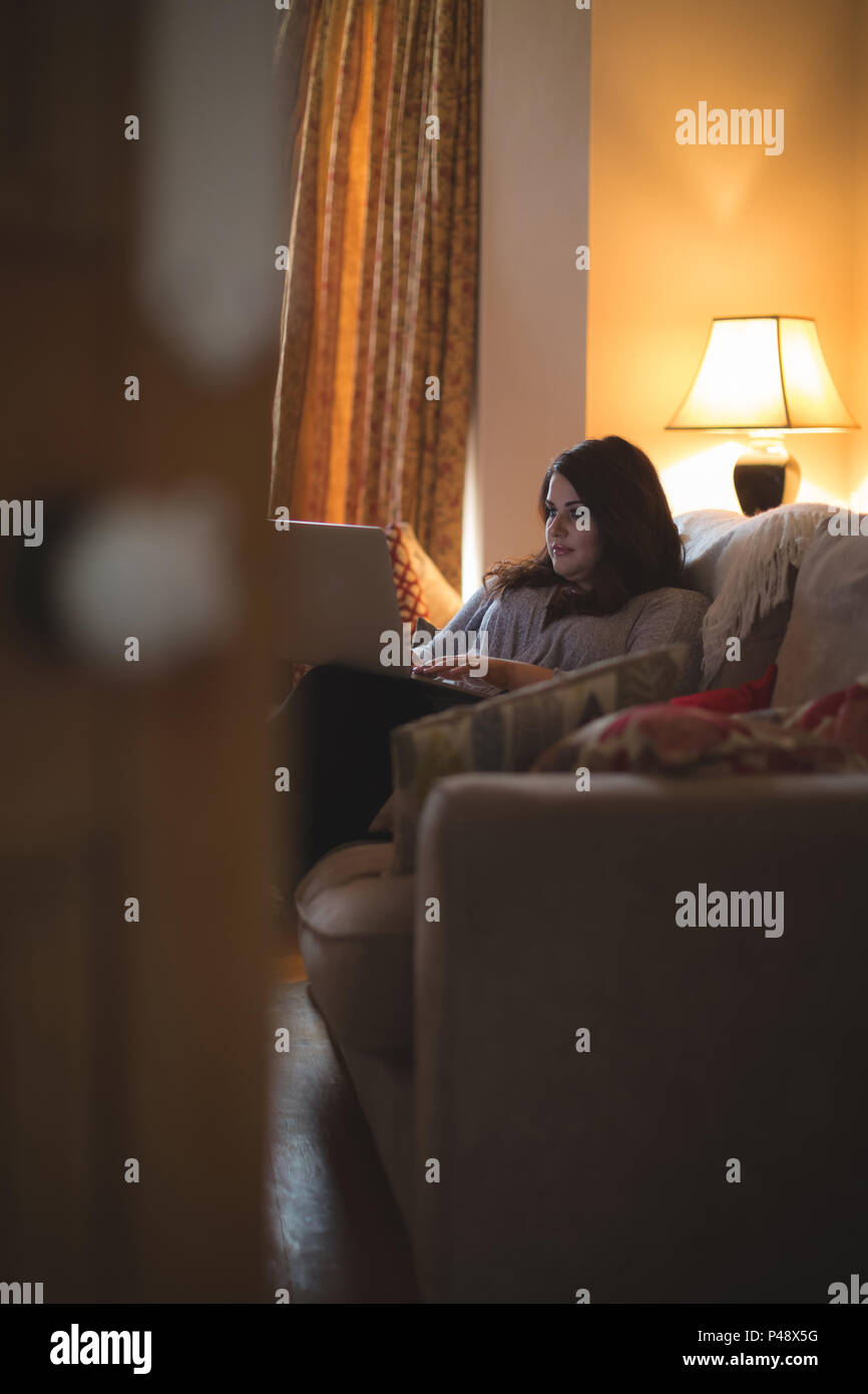 Female vlogger sitting on sofa while using laptop Stock Photo