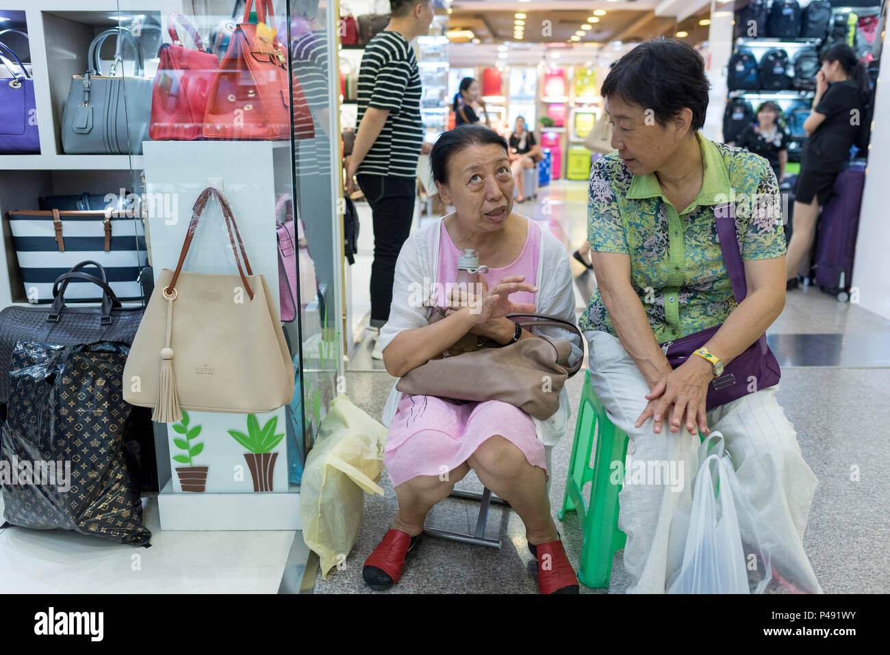 Two mature women friends take break while shopping in mall, Beijing, China Stock Photo