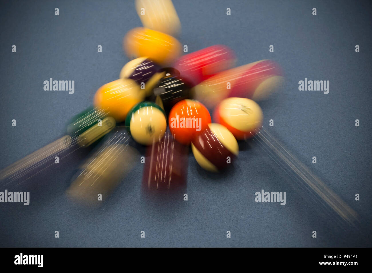 Motion shot of a cue ball breaking a rack on a pool table Stock Photo