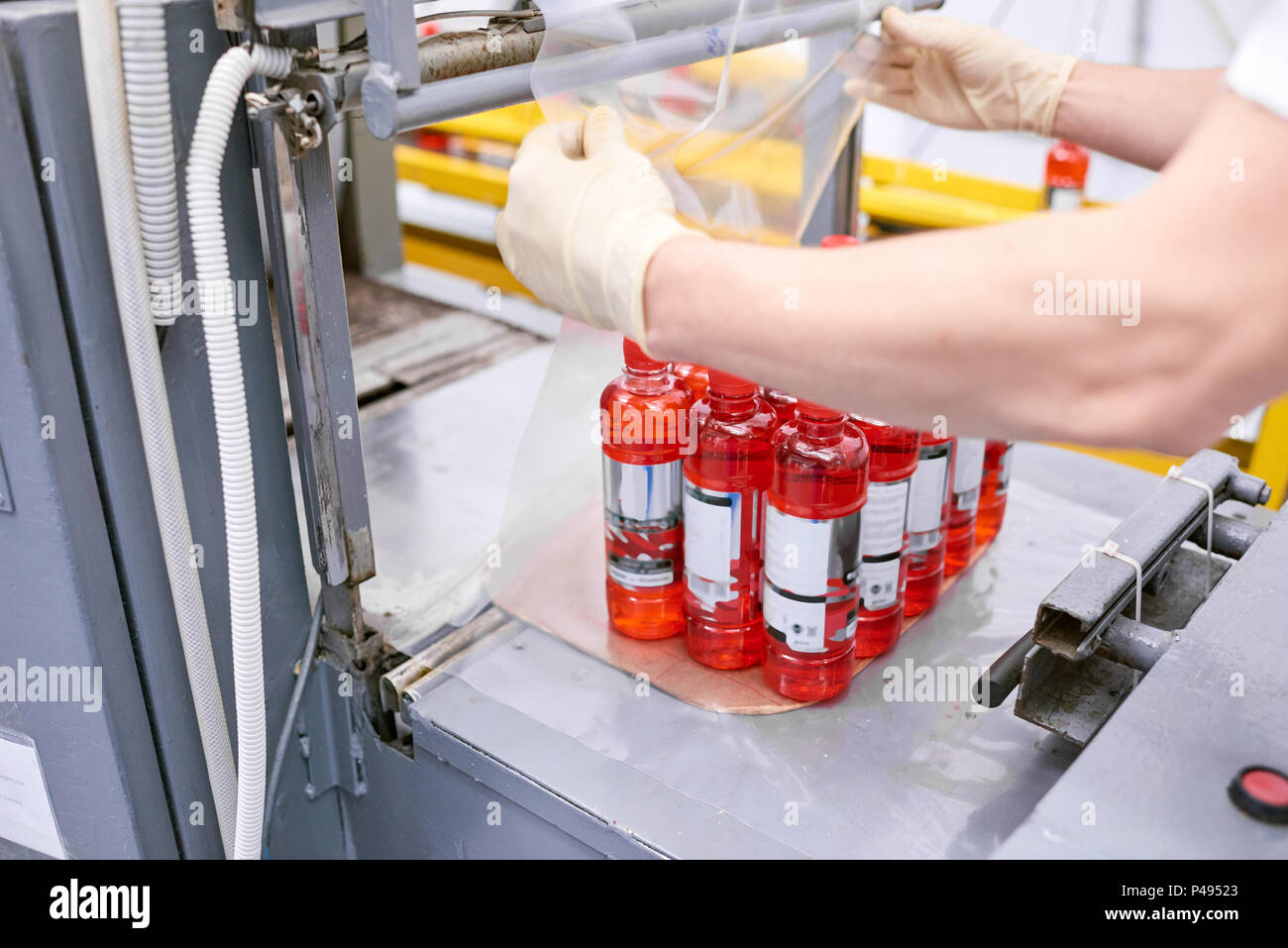 Factory worker packing full bottles into plastic film Stock Photo Alamy