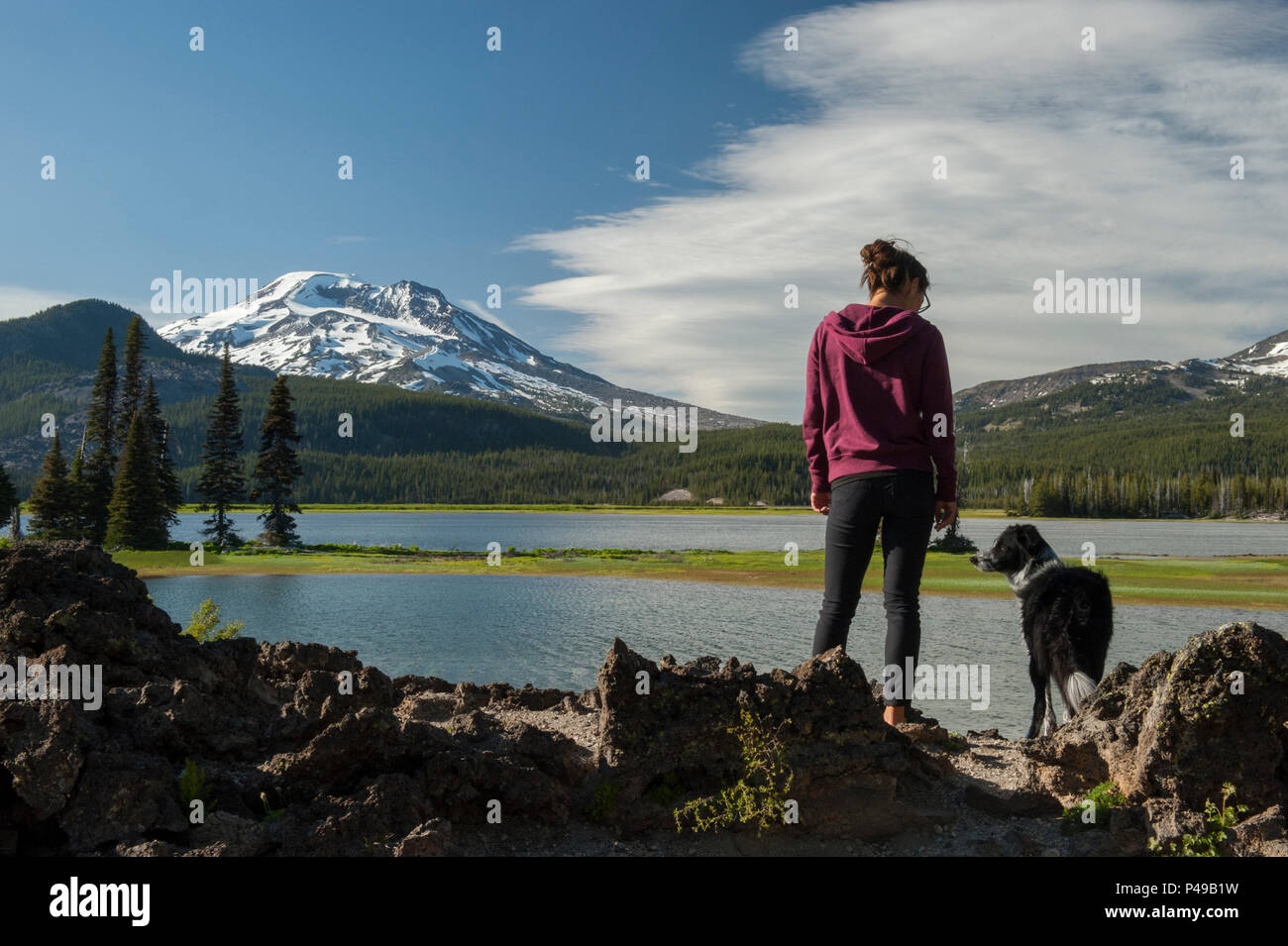 Model Released.  A young woman and her dog enjoy the view of the South Sister at the Ray Atkeson memorial viewpoint on Oregon's Sparks Lake Stock Photo