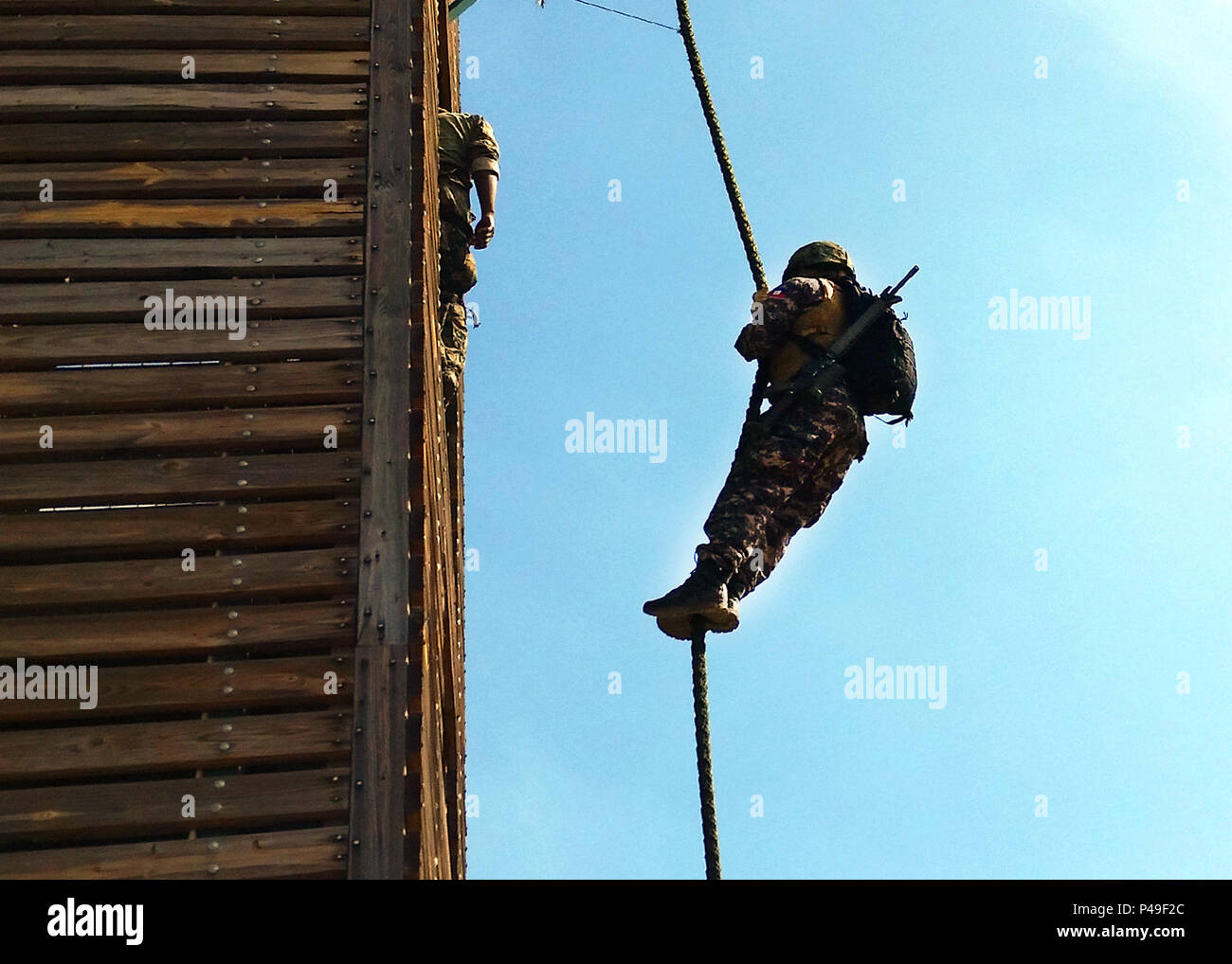 A partner nation servicemember fast ropes from a tower at the JDF Up ...