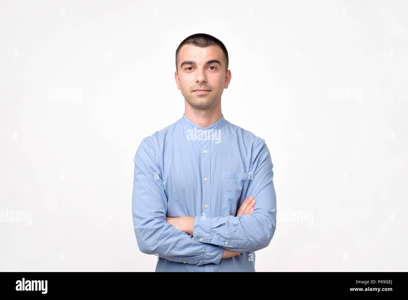 Portrait of happy fashionable handsome man in blue shirt crossing hands ...