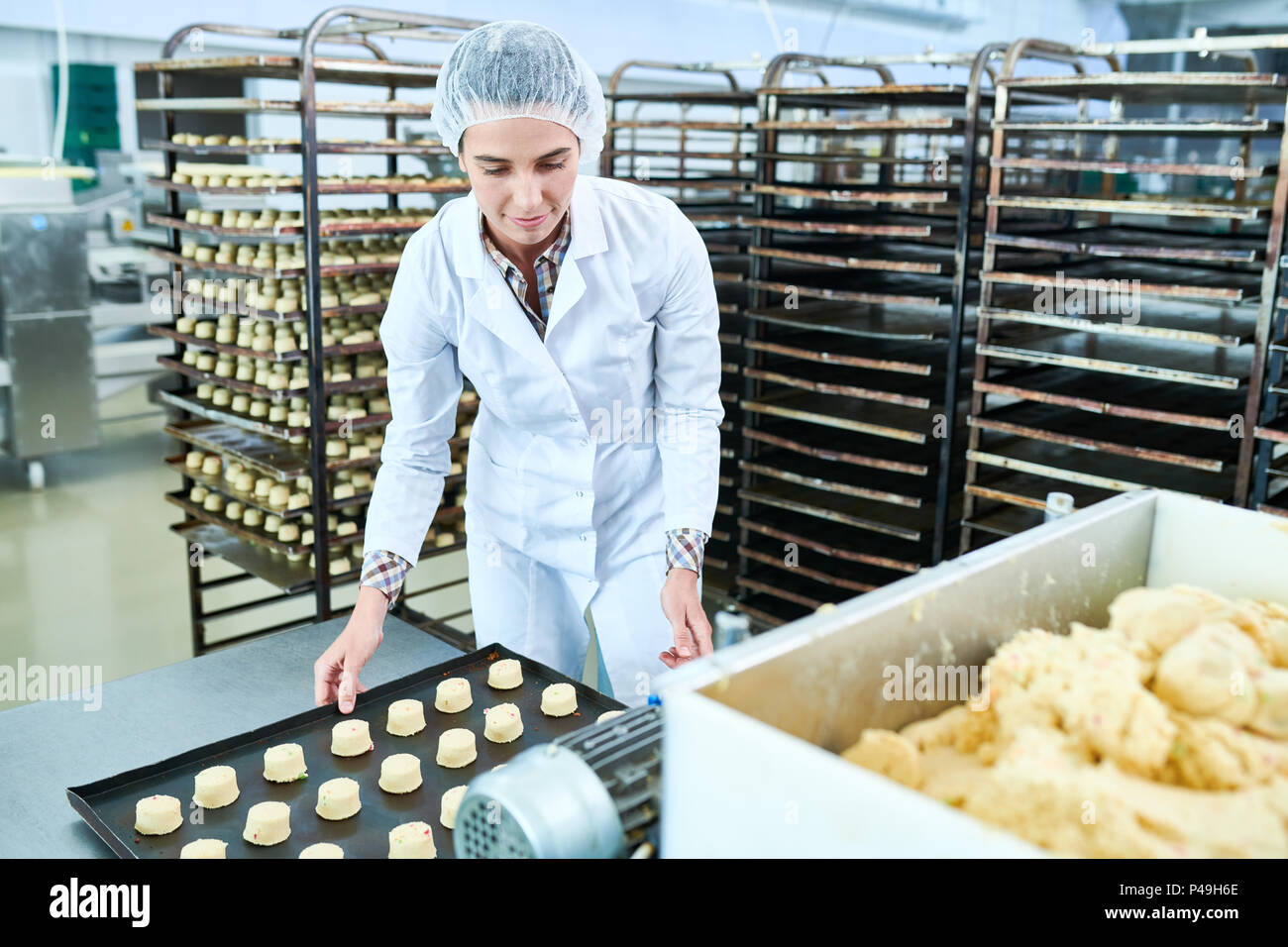 Confectionery factory worker holding tray with uncooked pastry Stock