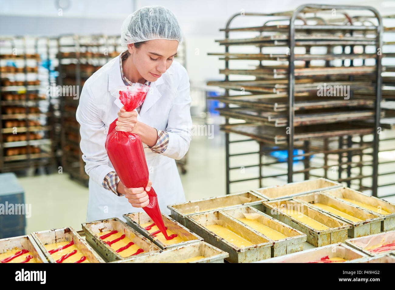 Confectionery factory employee using pastry bag Stock Photo