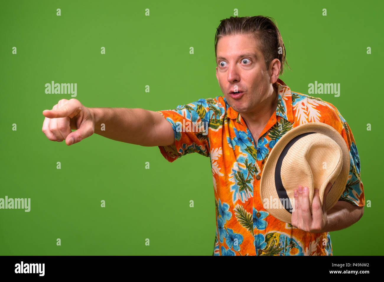 Mature tourist man ready for vacation against green background Stock Photo