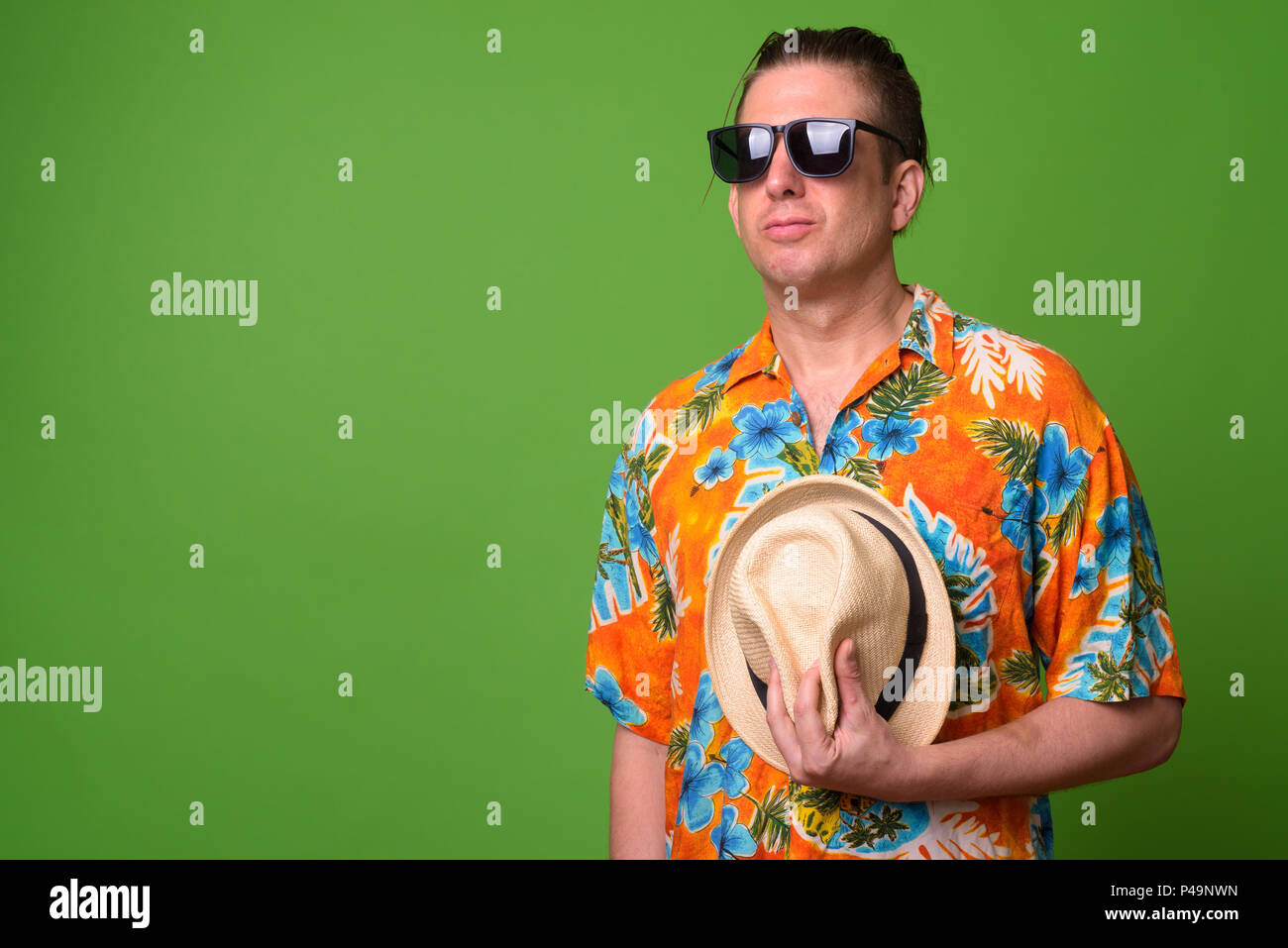 Mature tourist man ready for vacation against green background Stock Photo
