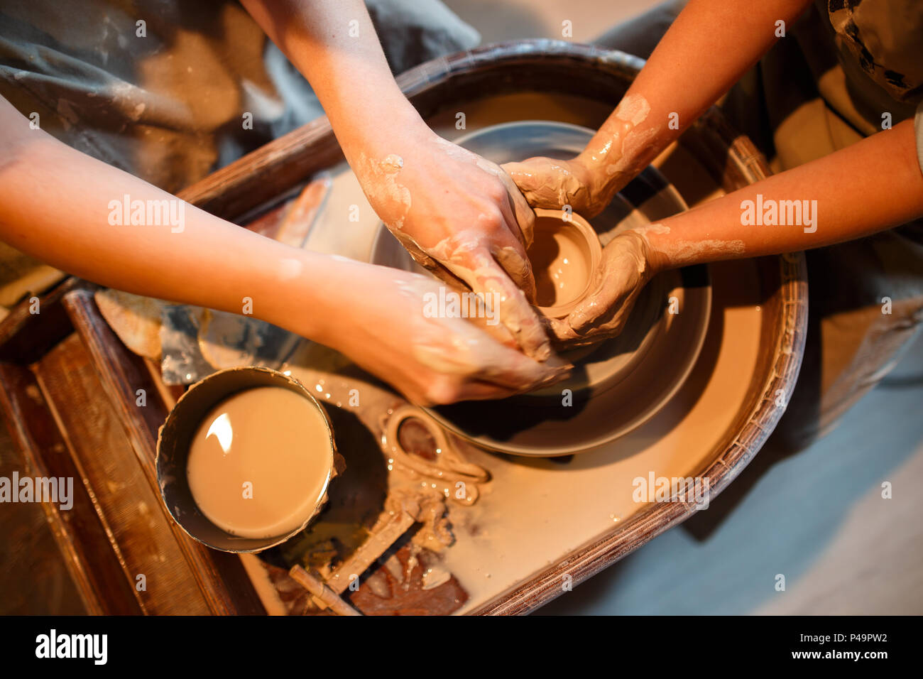 Master potter teaches the child to work on the Potter's wheel. Close up