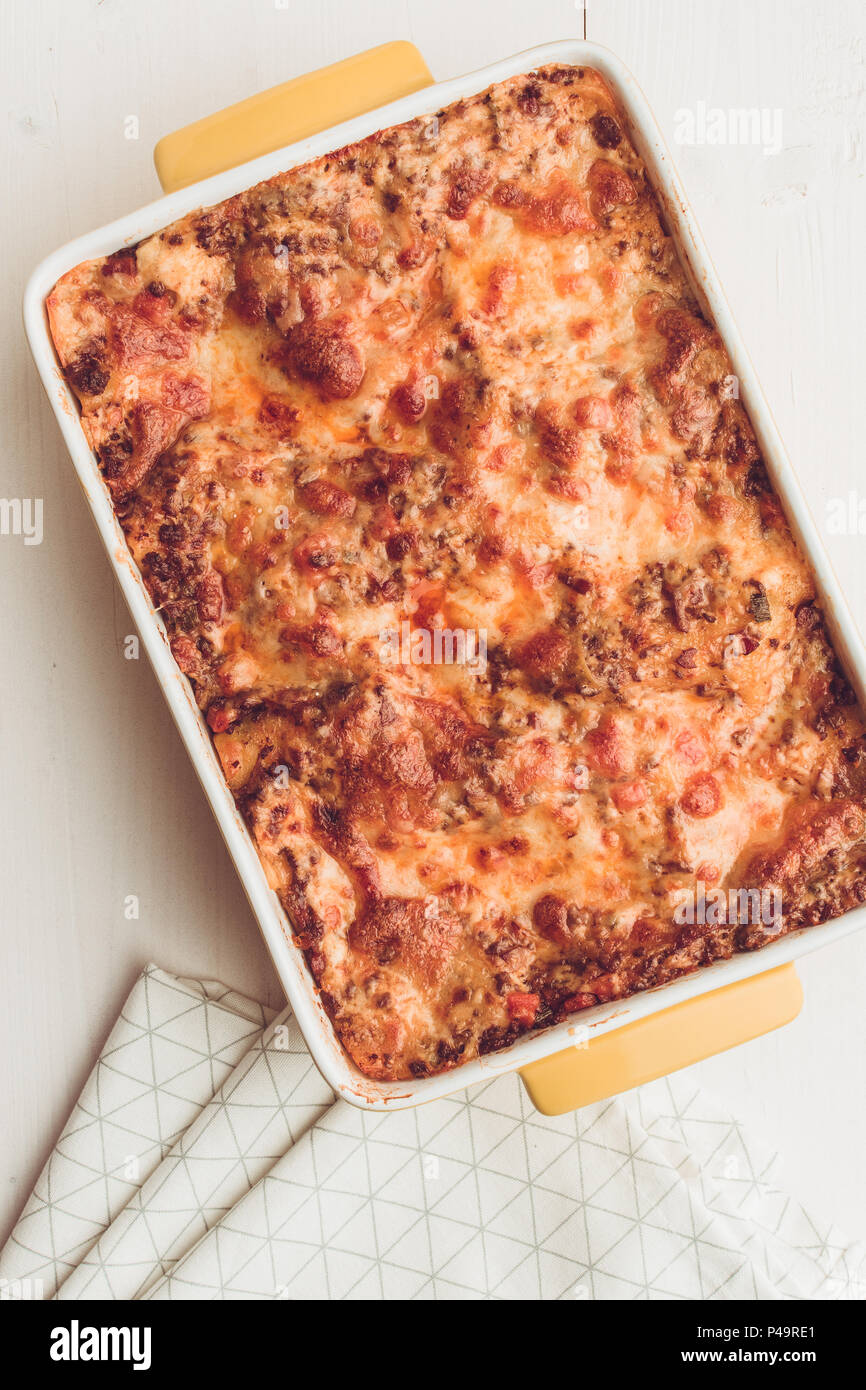 Lasagna Bolognese with Beef, Tomato Sauce and Green Basil on Rustic White Wooden Table Stock Photo