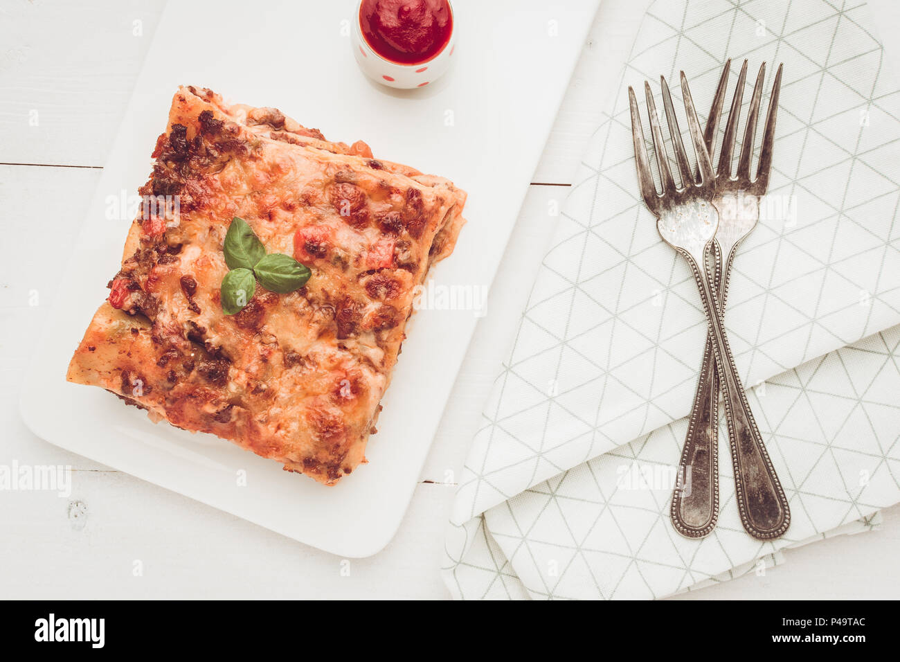 Homemade Lasagna with Minced Beef, Tomato Sauce and Fresh Basil on White Plate Stock Photo