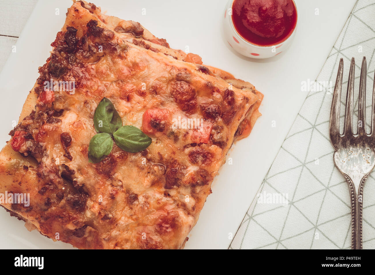 Homemade Lasagna with Minced Beef, Tomato Sauce and Fresh Basil on White Plate Stock Photo