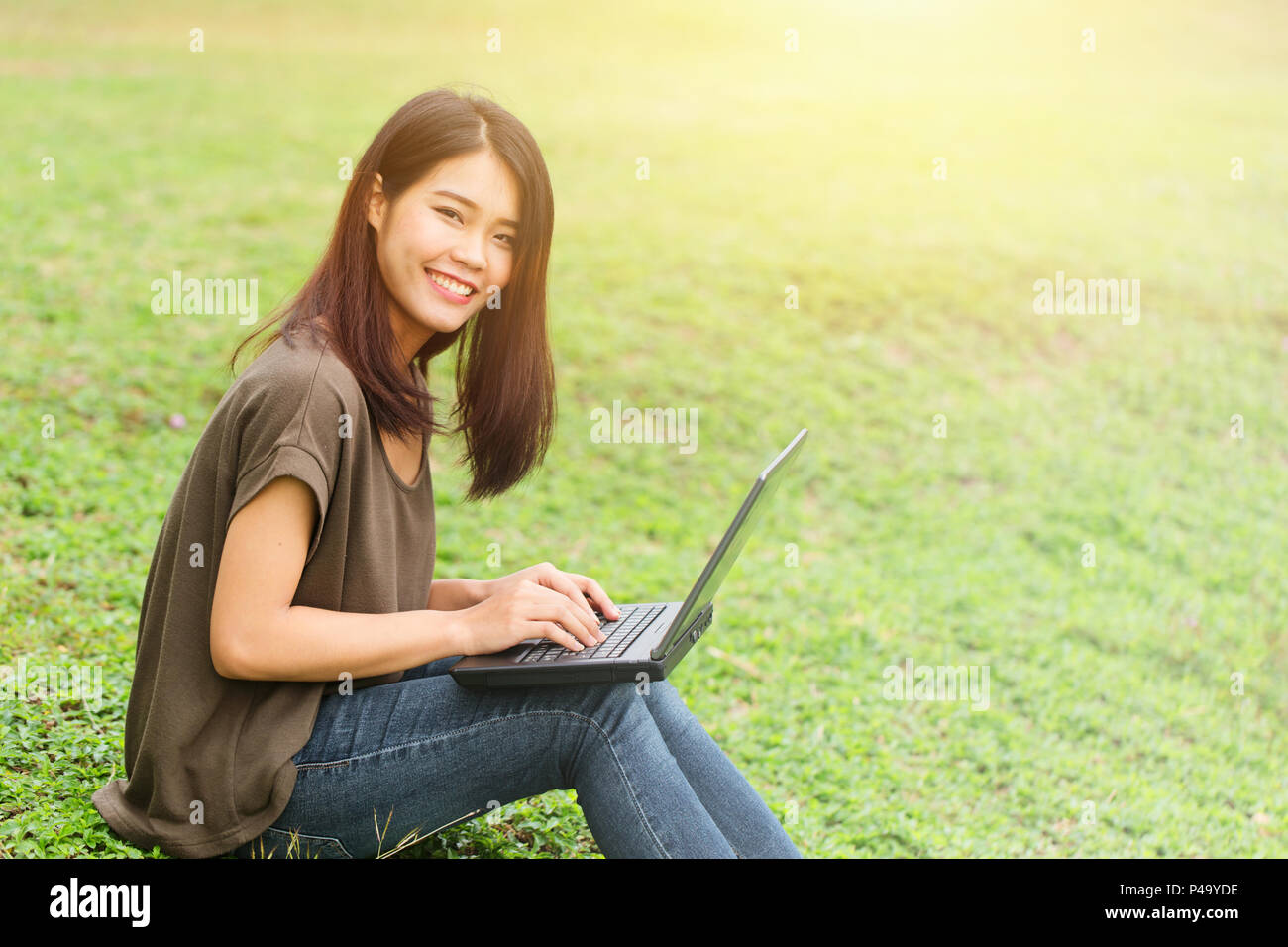 single asian teen smile student using laptop computer with business data working in university. Stock Photo
