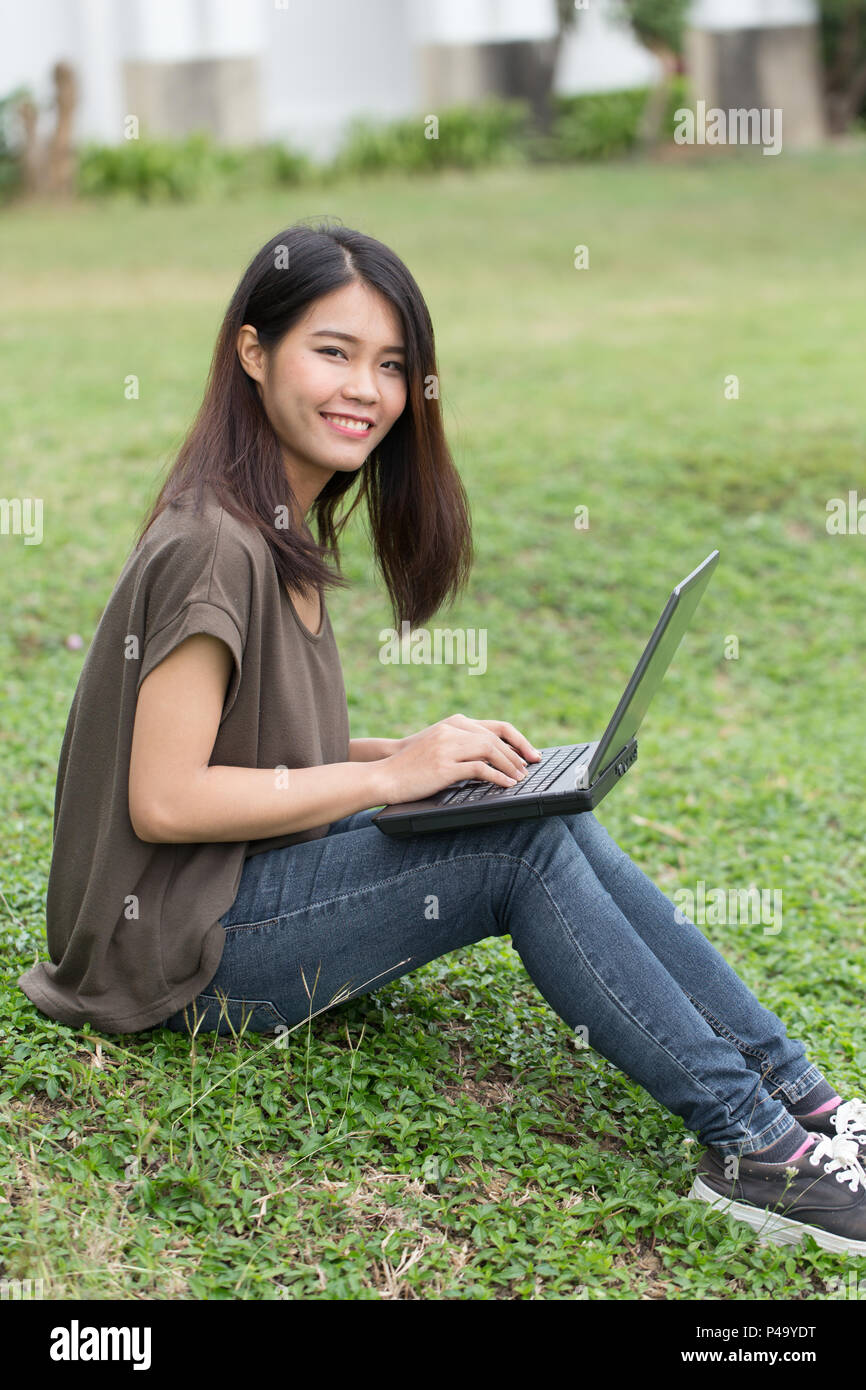 single asian teen smile student using laptop computer with business data working in university. Stock Photo