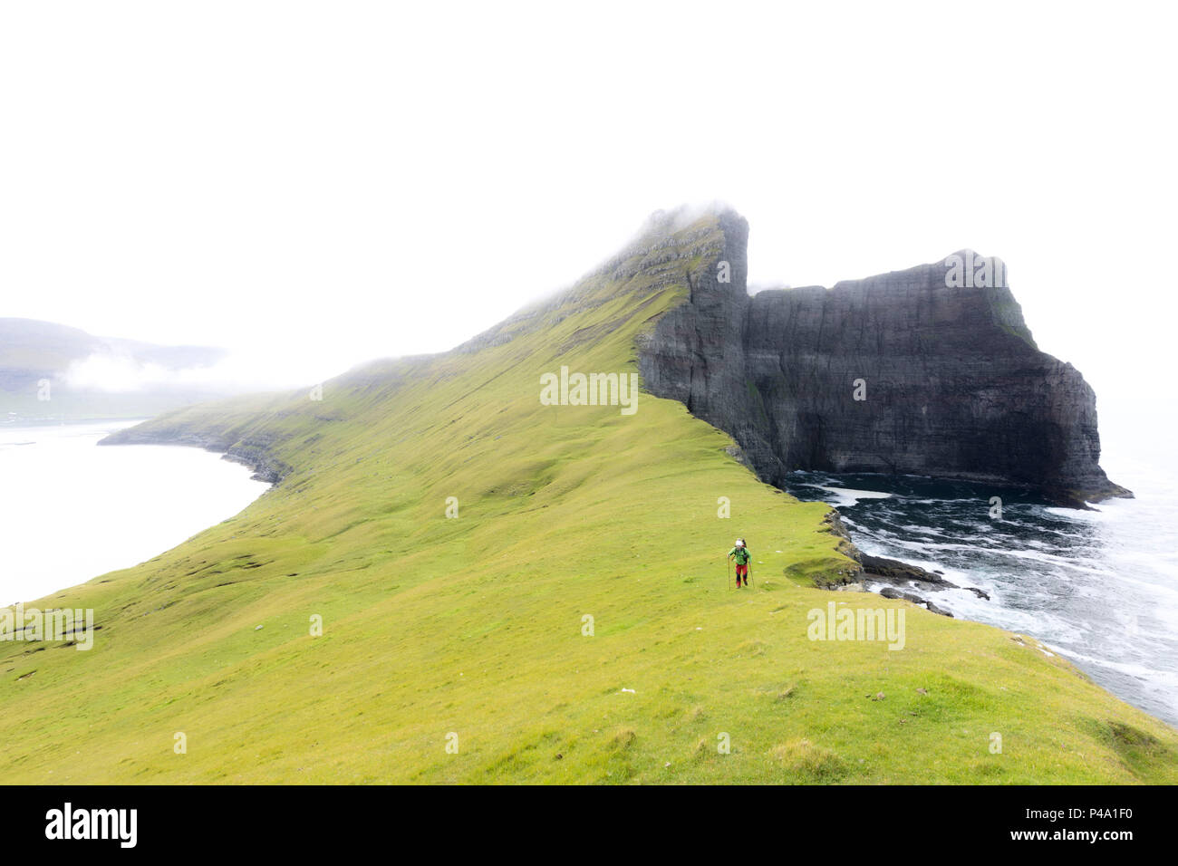 Hiker ventures on cliffs, Drangarnir, Vagar Island, Faroe Islands Stock Photo