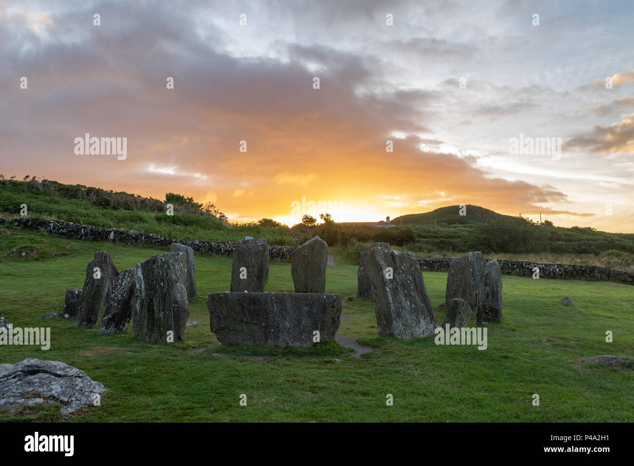 The sun rise over the Drombeg Stone Circle marking the start of the summer solstice, the longest day of the year. Drombeg is an ancient stone circle near Glandore, believed to be among other things a bronze age calendar marking the winter solstice when the sun sets over the Axial stone. Stock Photo