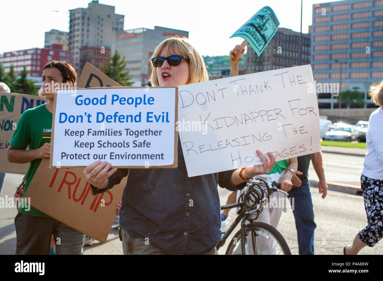DULUTH, MINNESOTA, USA - June 20, 2018: A woman protester holds signs as a large crowd of protesters march in front of Amsoil arena while President Donald Trump speaks at a rally Wednesday night. Credit: Theresa Scarbrough/Alamy Live News Stock Photo
