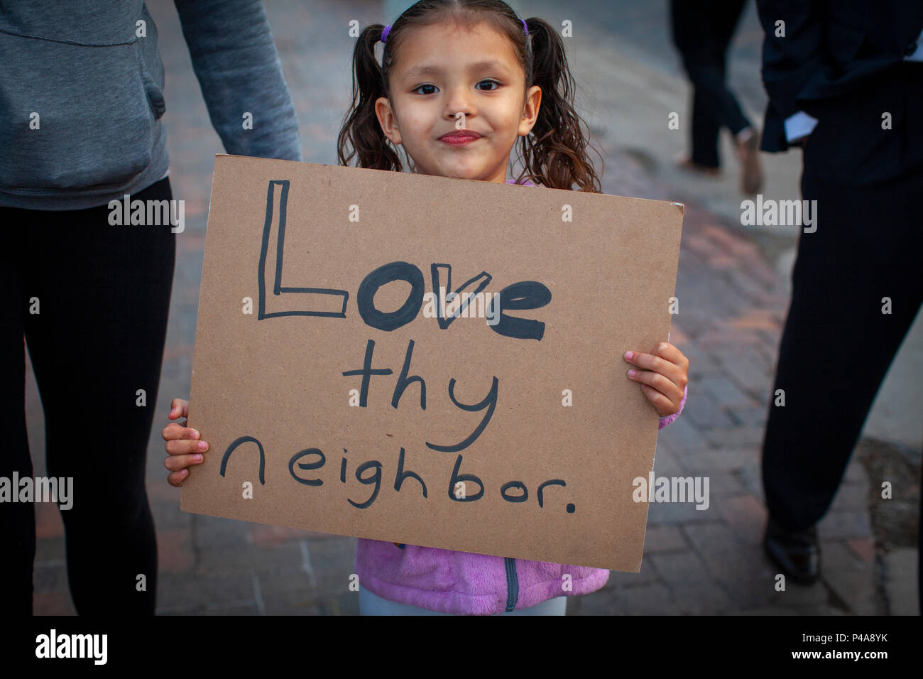 DULUTH, MINNESOTA, USA - June 20, 2018: A little girl protester holds up her sign 'Love thy Neighbor' while President Donald Trump speaks at a rally Wednesday night. Credit: Theresa Scarbrough/Alamy Live News Stock Photo