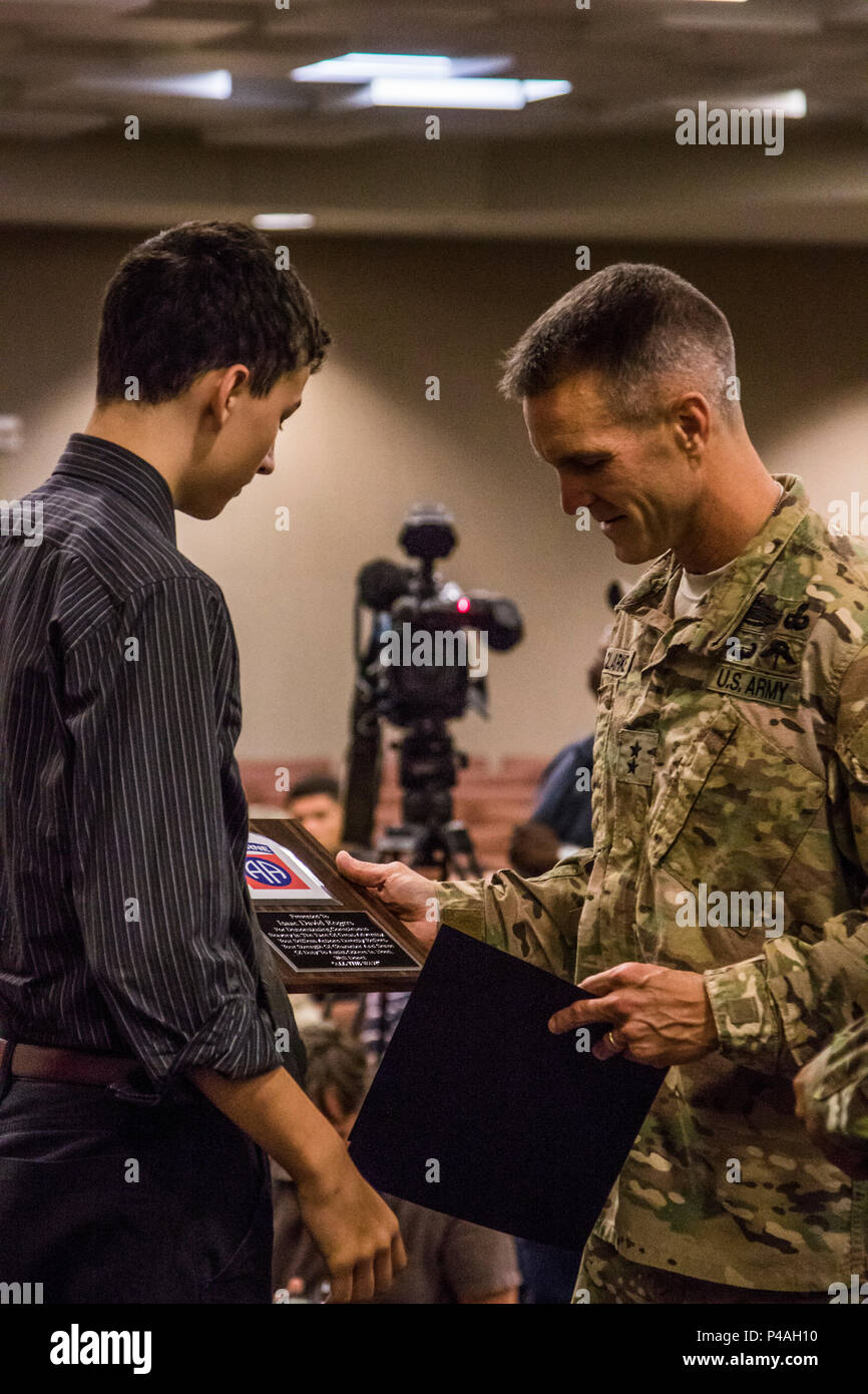 Maj. Gen. Richard Clarke, commander of the 82nd Airborne Division, presents  Isaac Rogers, the oldest son of Spc. Benjamin Rogers, 82nd Combat Aviation  Brigade, a certificate on behalf of the Division for