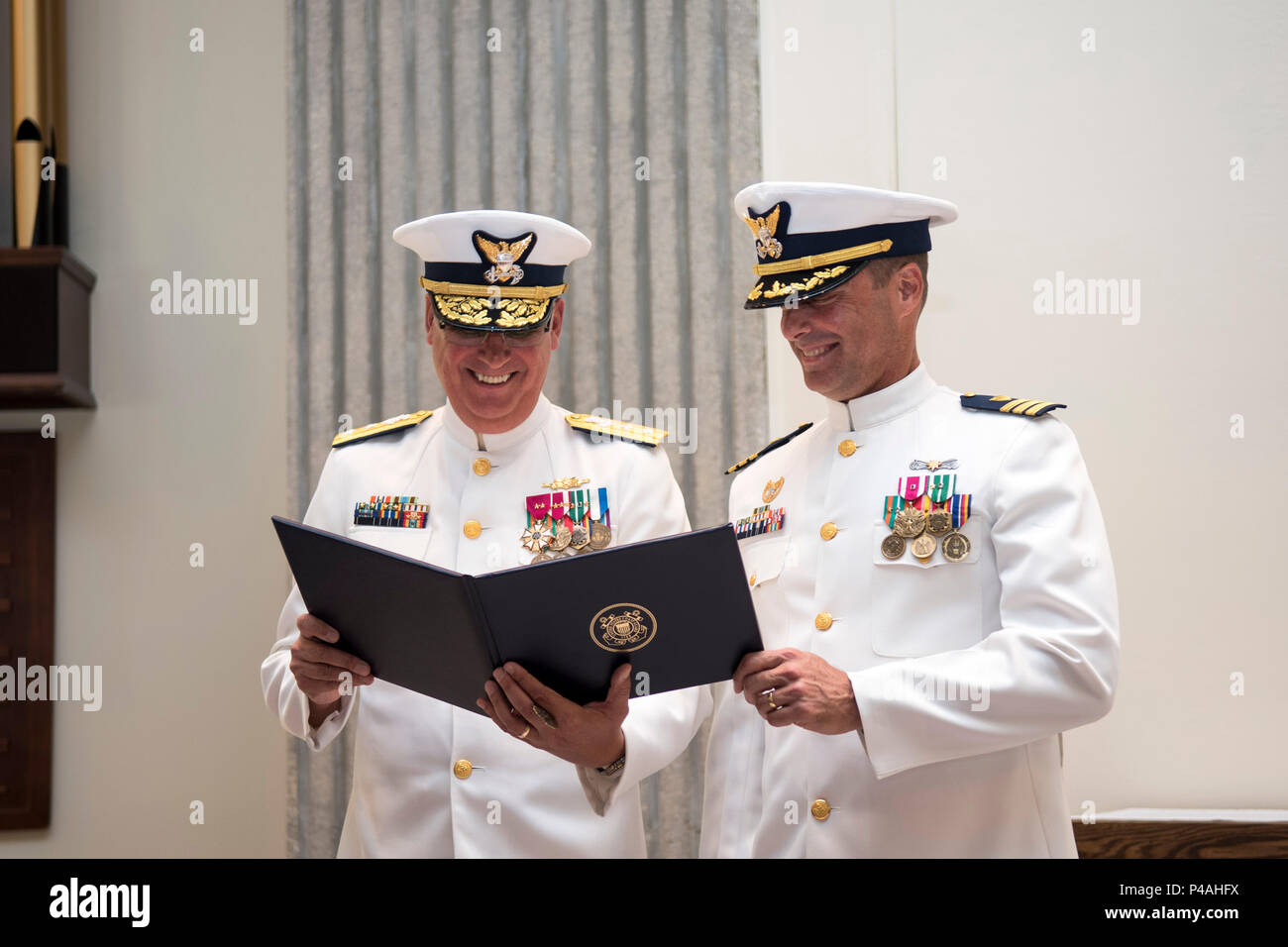 Rear Adm. Scott A. Buschman, commander of the Coast Guard 7th District, left, presents Cmdr. Kevin Jones, commanding officer of the Coast Guard Maritime Force Protection Unit Kings Bay, with an award during the unit's change of command ceremony at Naval Submarine Base Kings Bay, Georgia, June 24, 2016. At the ceremony, Cmdr. Jones transferred command of the unit to Cmdr. Joseph Gaskill. U.S. Navy photo by Petty Officer 2nd Class Bradley Gee Stock Photo