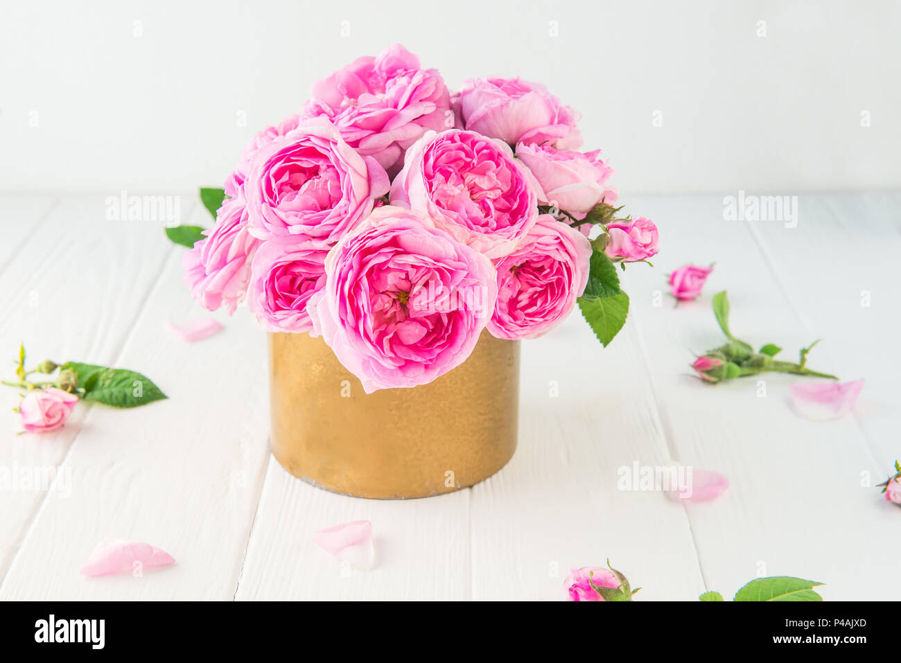 Close up tender pink tea roses bouquet in vintage golden pot on the ...