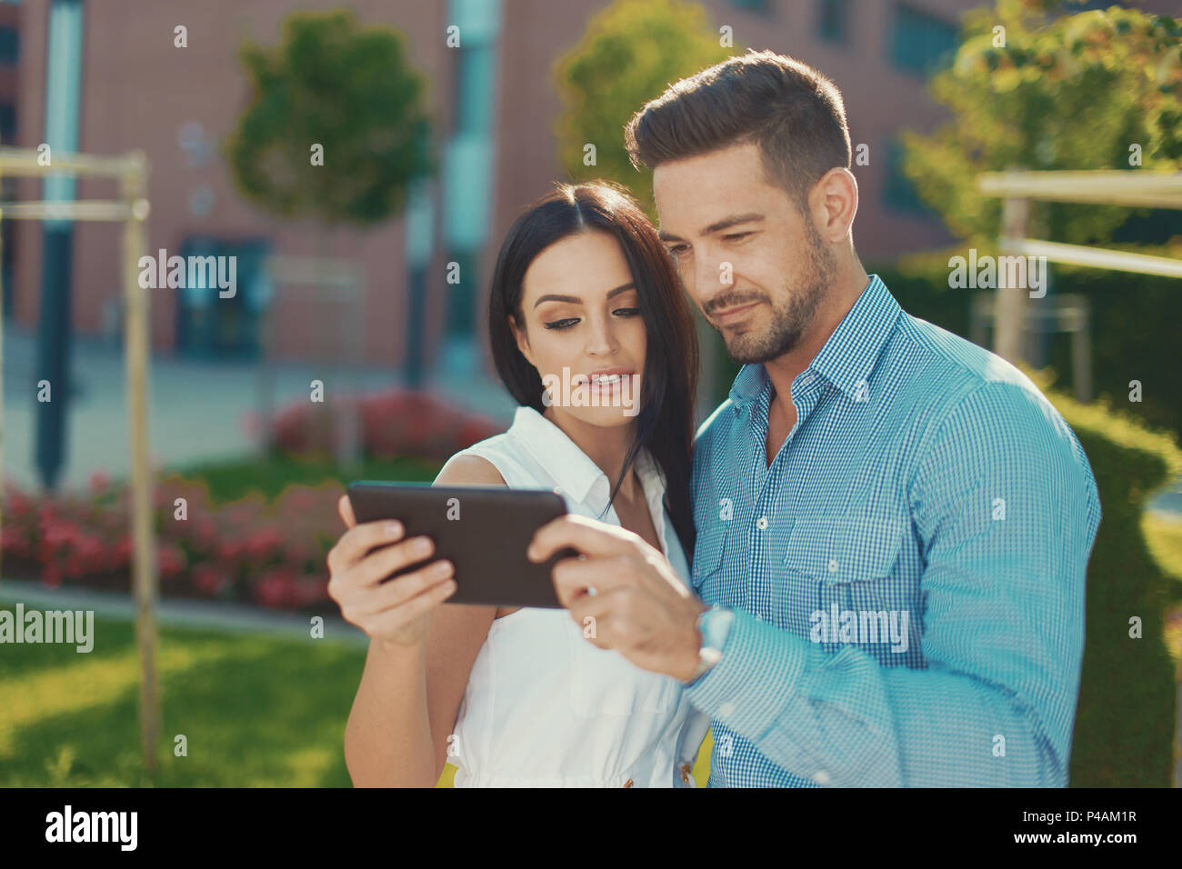 Young couple browsing on digital tablet, outdoors, color graded Stock Photo