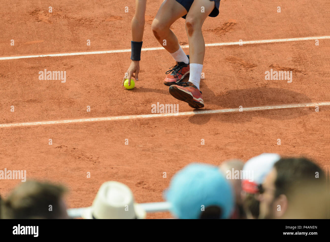 Ball boy picking up the tennis ball, running on a tennis court, with