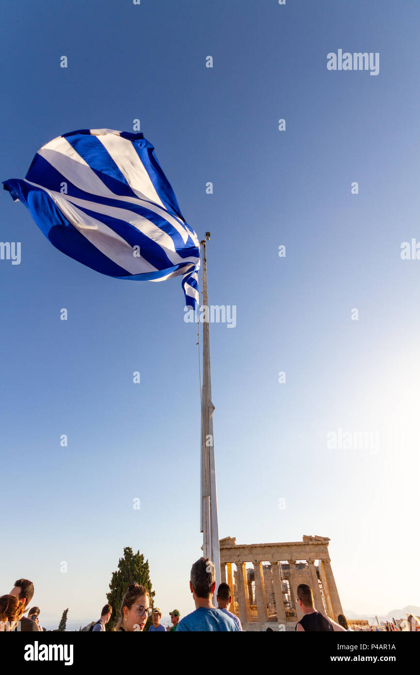 Athens, Greece - June 9, 2018: Greek flag waving on a mast at the Acropolis surrounded by tourists with the Parthenon visible in the background Stock Photo