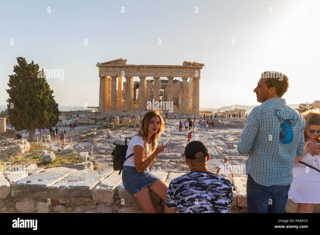 Athens, Greece - June 9, 2018: Tourists posing for photos on the Acropolis against the Parthenon on a summer afternoon Stock Photo