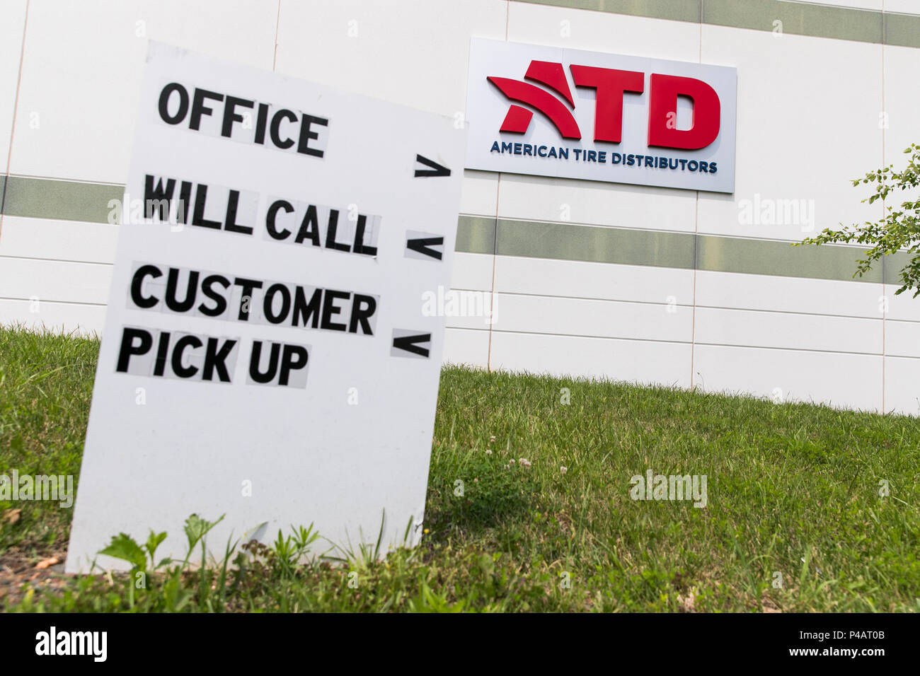 A logo sign outside of a facility occupied by American Tire