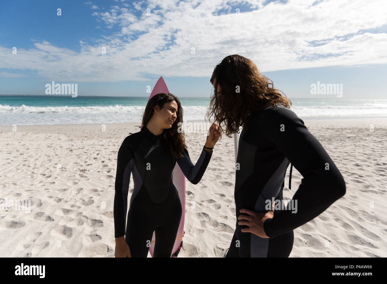 Surfer couple standing in the beach Stock Photo - Alamy