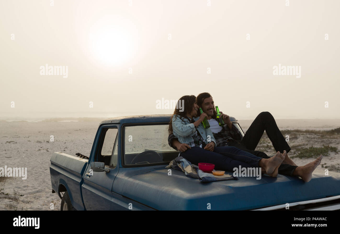 Couple having beer on a pickup truck bonnet Stock Photo - Alamy