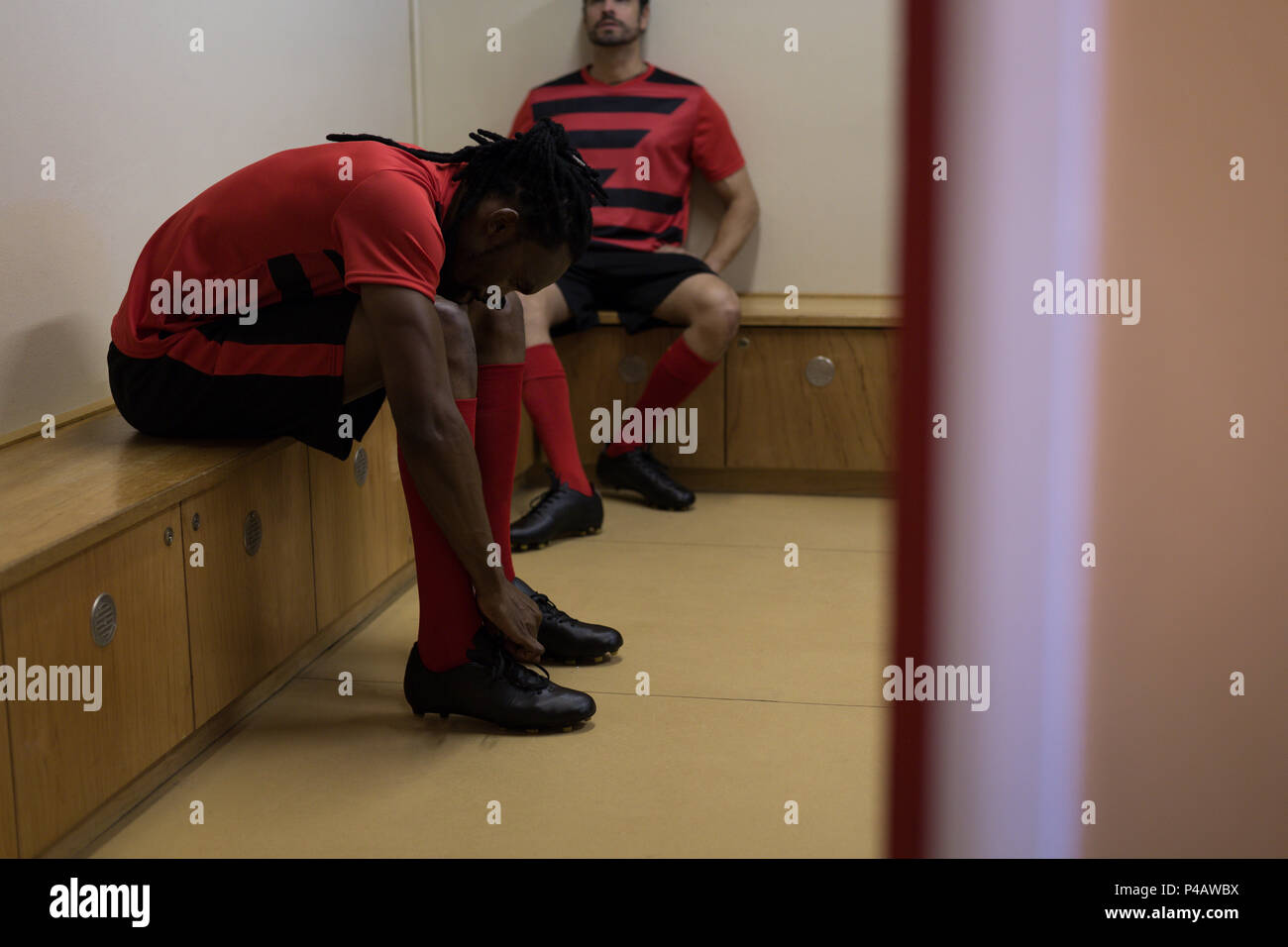 Football player tying his shoe lace in dressing room Stock Photo Alamy