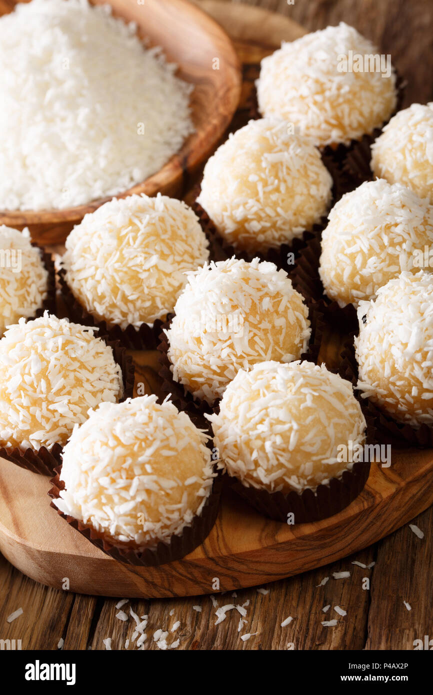 Brazilian Coconut Kisses (Beijinhos de Coco) condensed milk and coconut flakes close-up on the table. Vertical Stock Photo