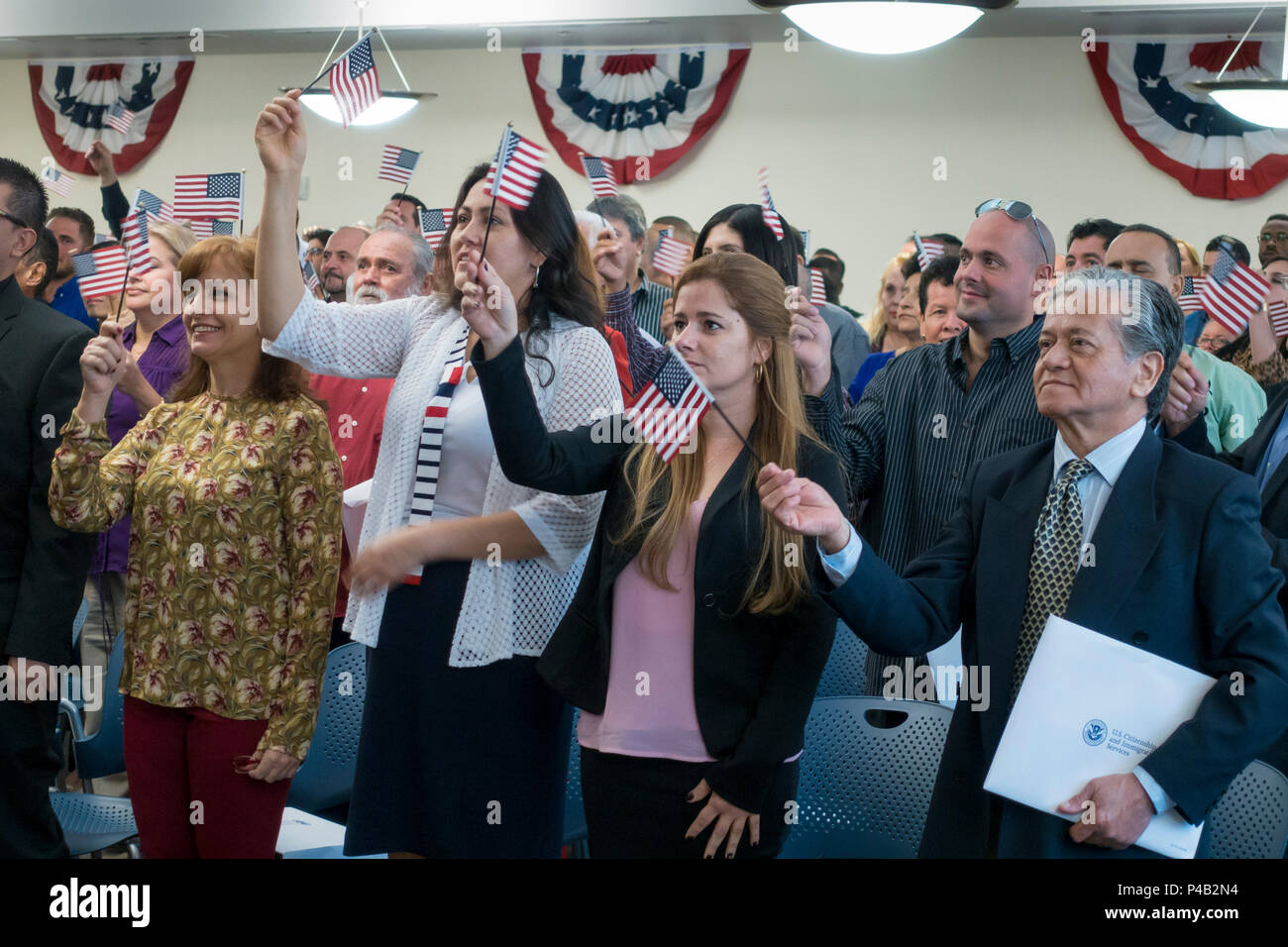 Just sworn in as American Citizens, immigrants wave flags and hold