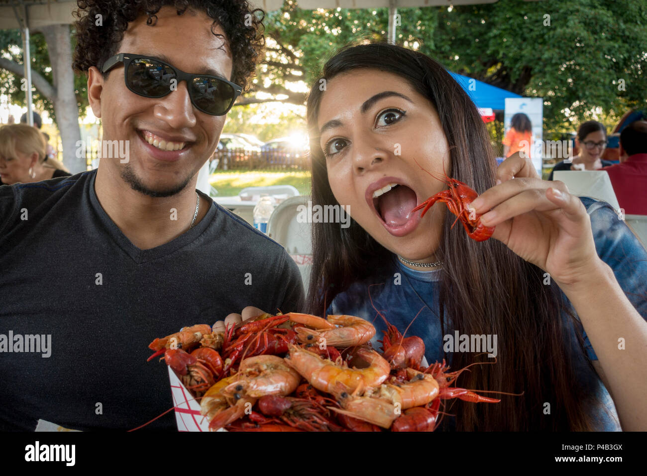 College age Hispanic couple picnic outdoors on seafood and have fun goofing off, Miami, Florida Stock Photo