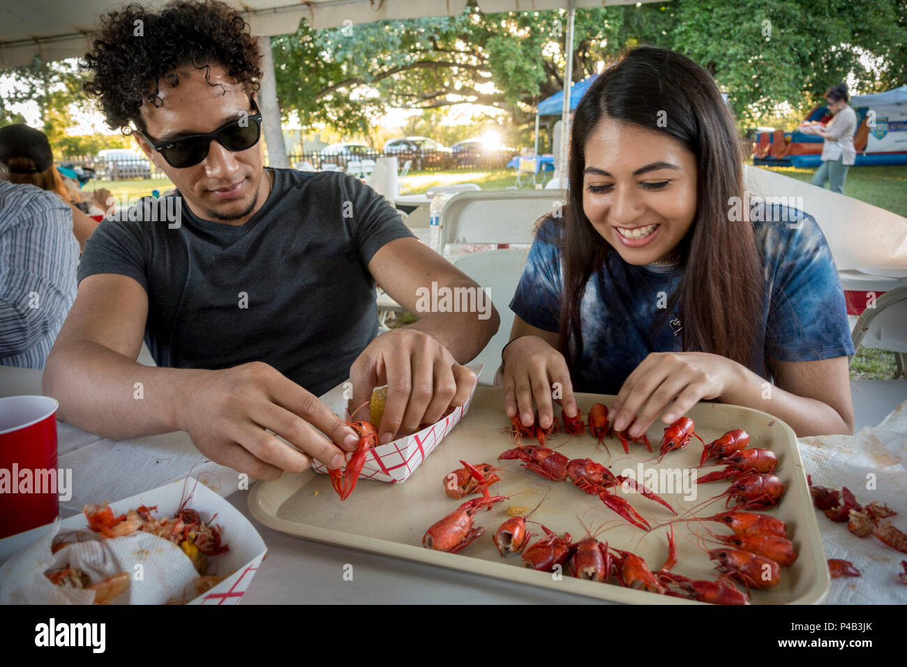 College age Hispanic couple picnic outdoors on seafood and have fun goofing off, Miami, Florida Stock Photo