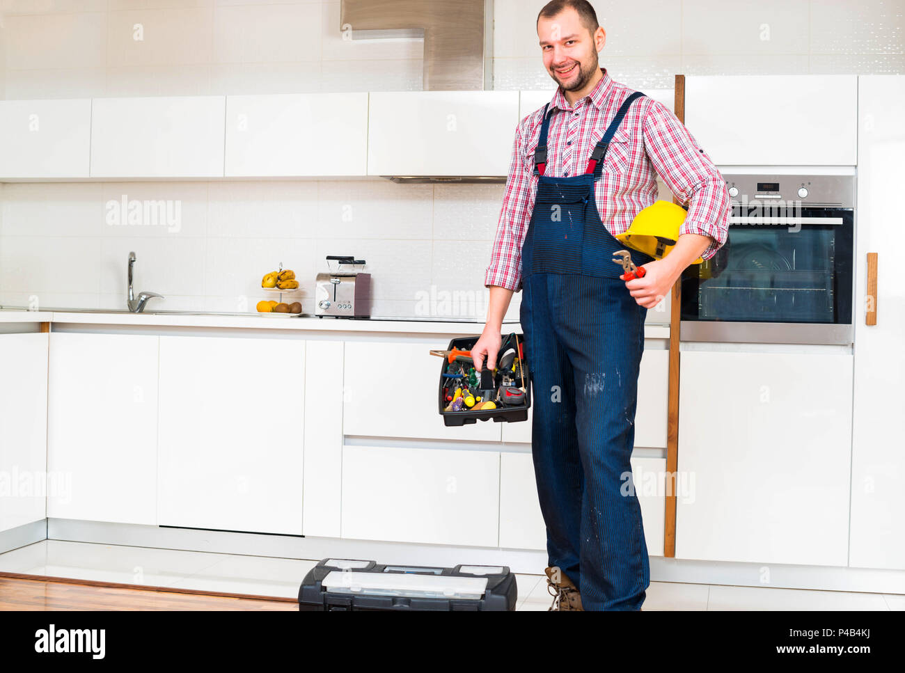 Workman holding his toolbox in the kitchen Stock Photo