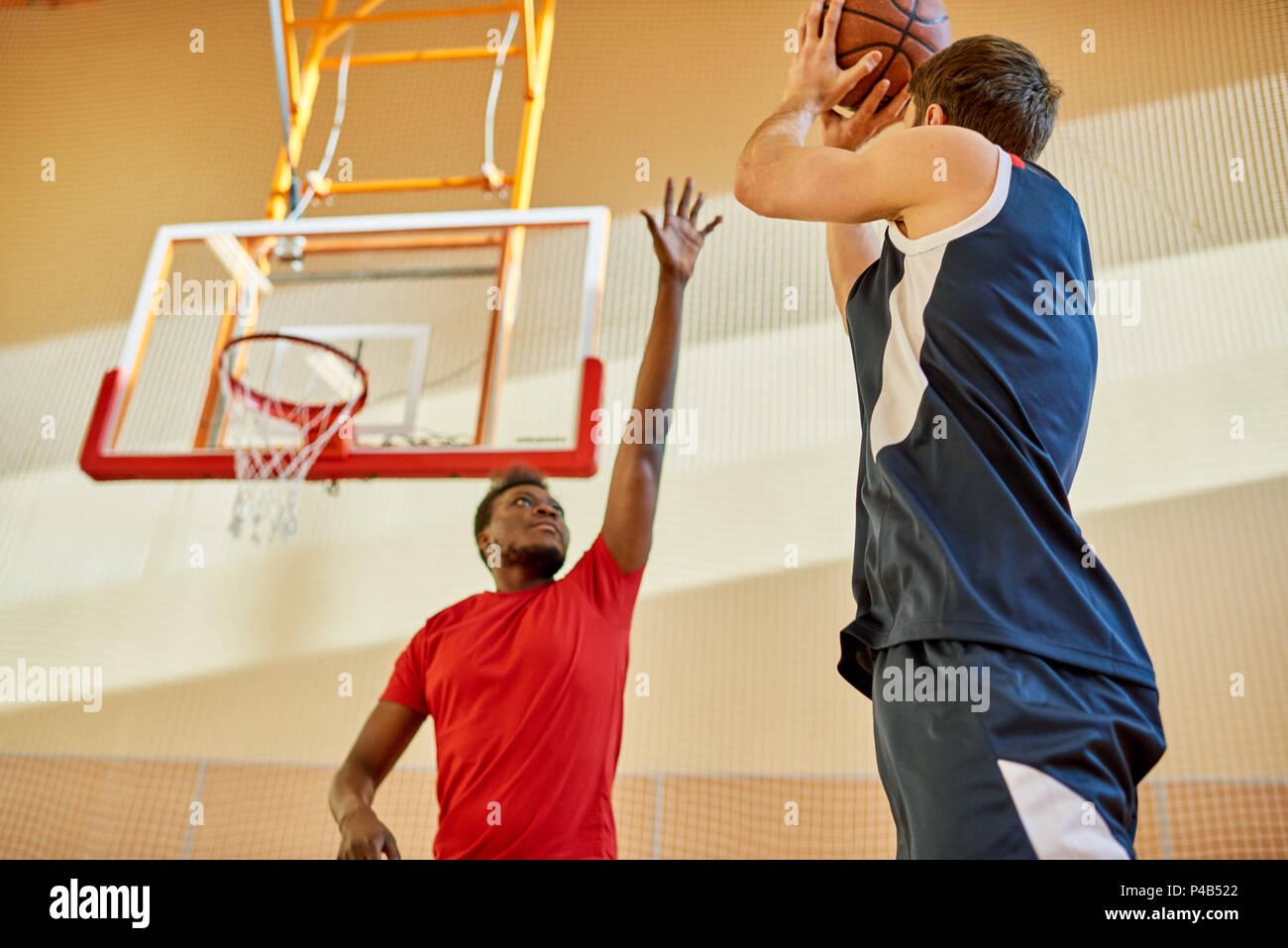 Two men playing basketball in gym Stock Photo