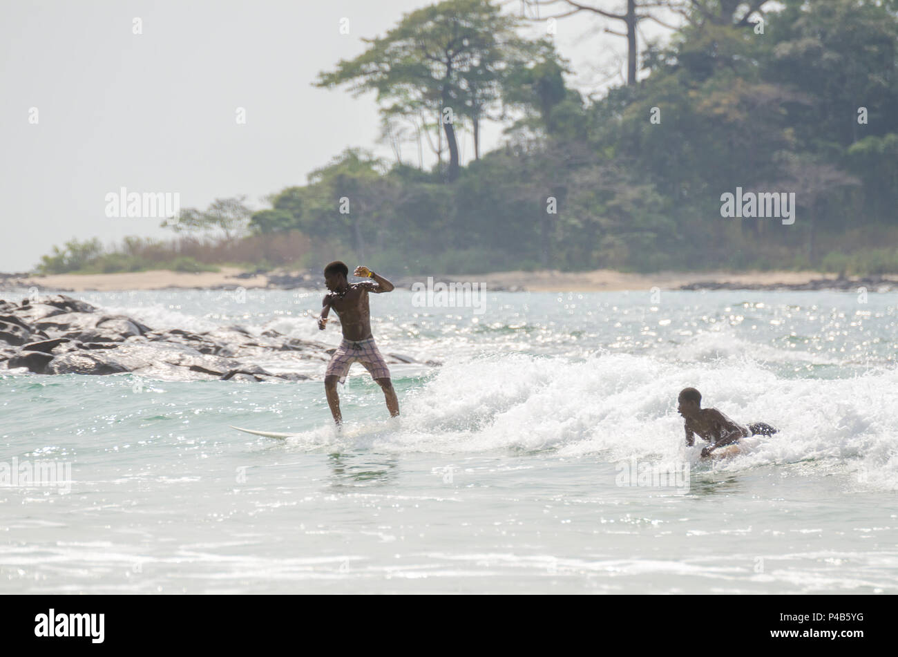 Bureh Beach, Sierra Leone - January 11, 2014: Two unidentified young African boys surfing at the only surf spot in the country Stock Photo