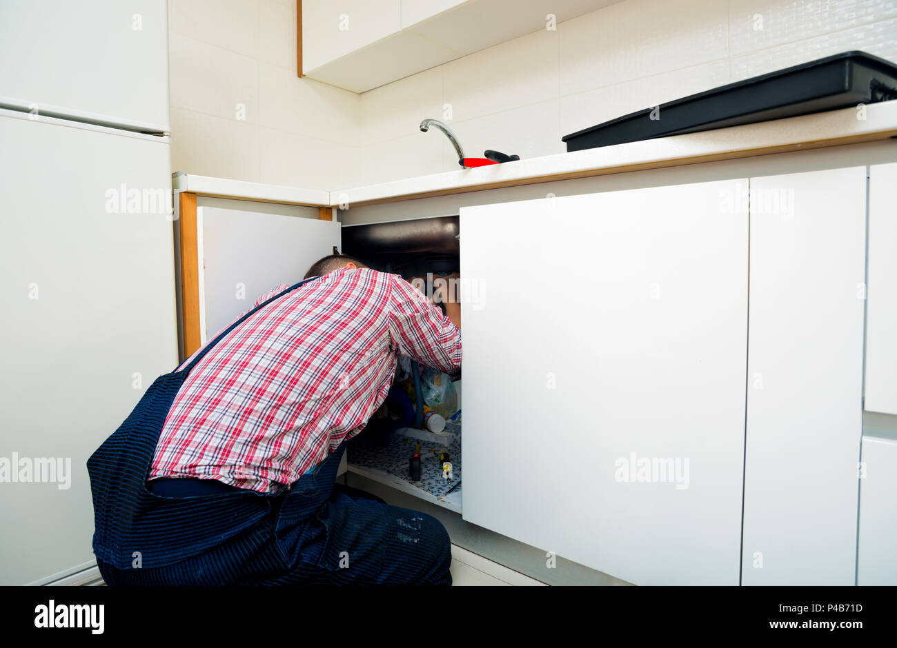 Worker repairs the leakage problem in the kitchen sink Stock Photo