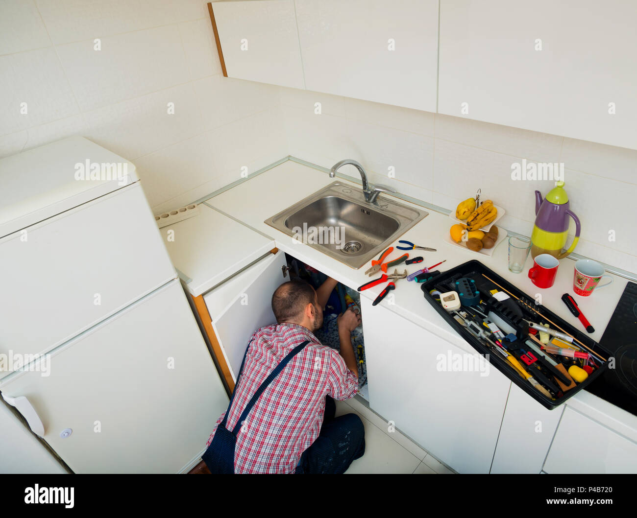 Worker repairs the leakage problem in the kitchen sink Stock Photo