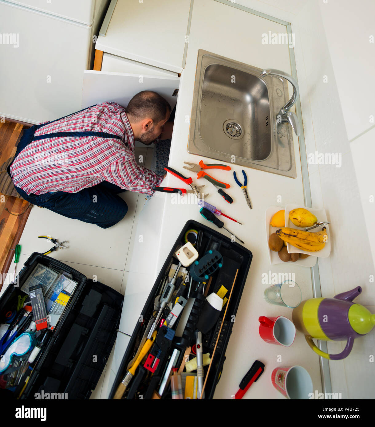 Worker repairs the leakage problem in the kitchen sink Stock Photo