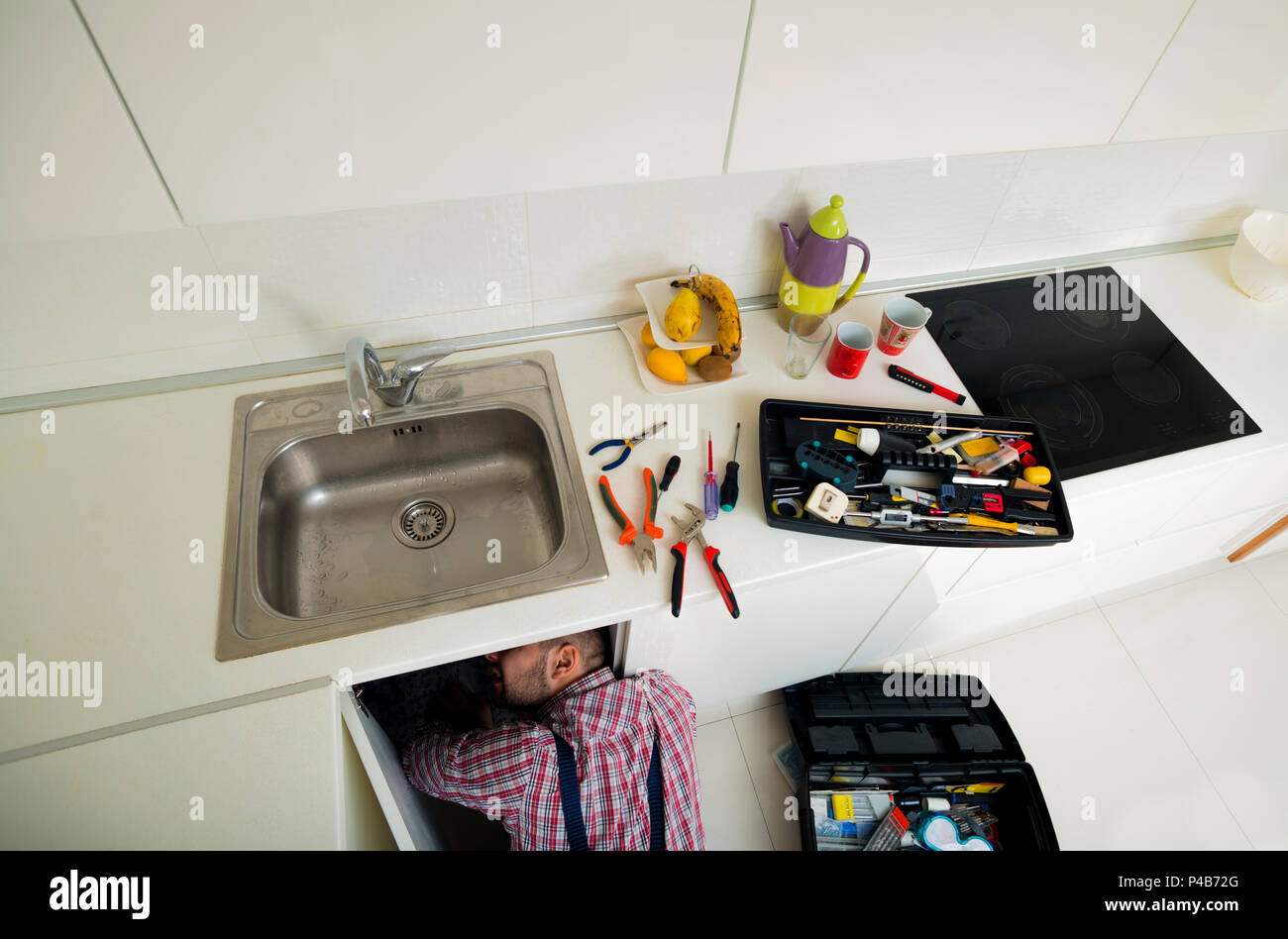 Worker repairs the leakage problem in the kitchen sink Stock Photo
