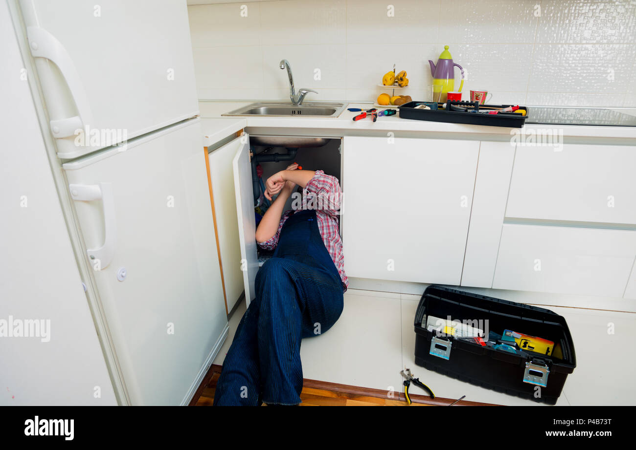 Worker repairs the leakage problem in the kitchen sink Stock Photo