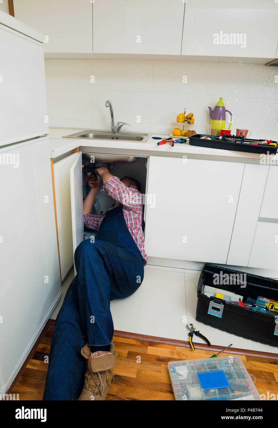 Worker repairs the leakage problem in the kitchen sink Stock Photo