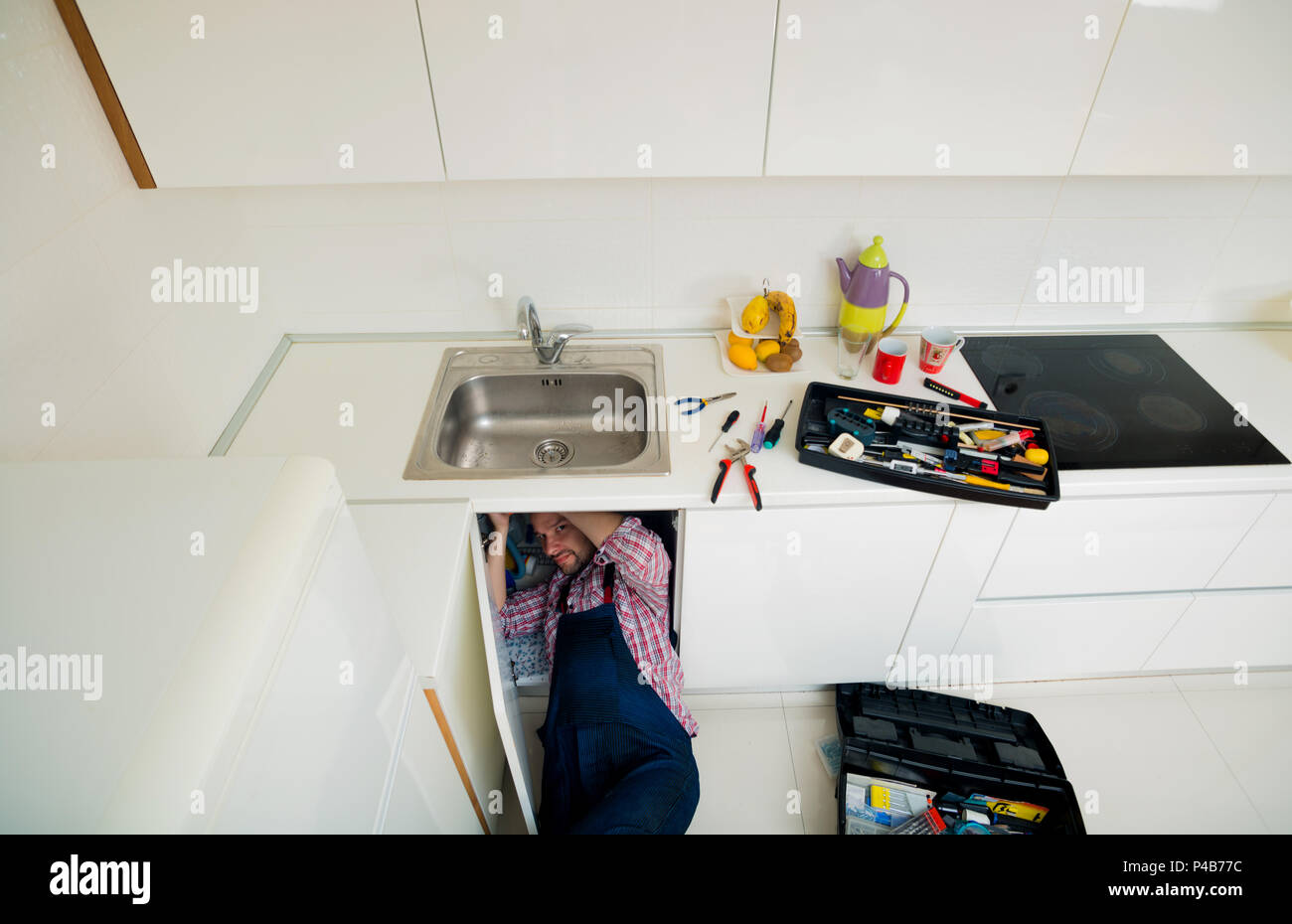 Worker repairs the leakage problem in the kitchen sink Stock Photo