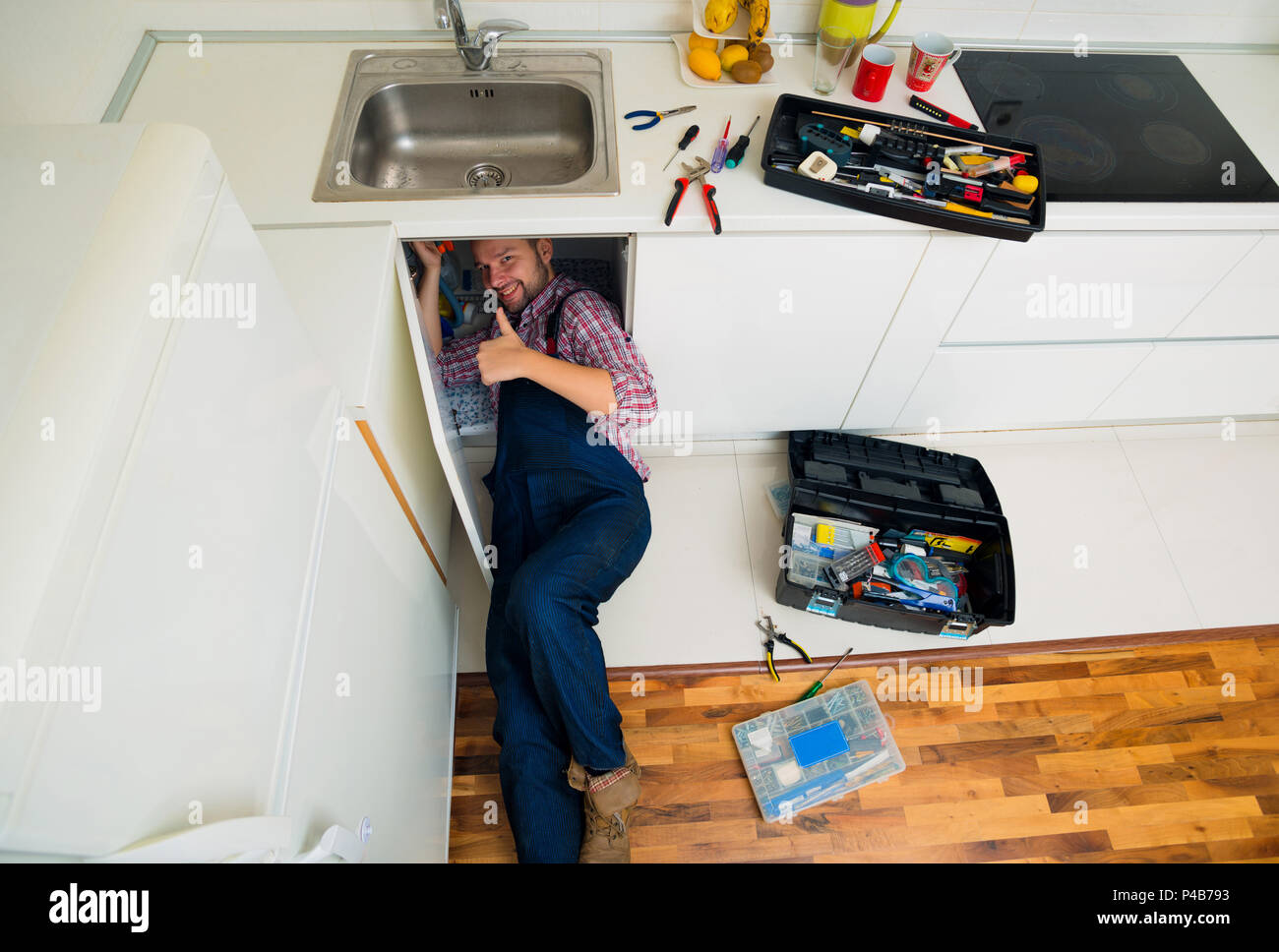 Worker repairs the leakage problem in the kitchen sink Stock Photo