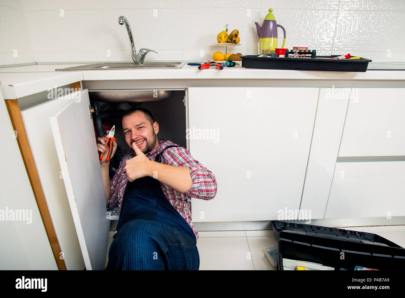 Worker repairs the leakage problem in the kitchen sink Stock Photo